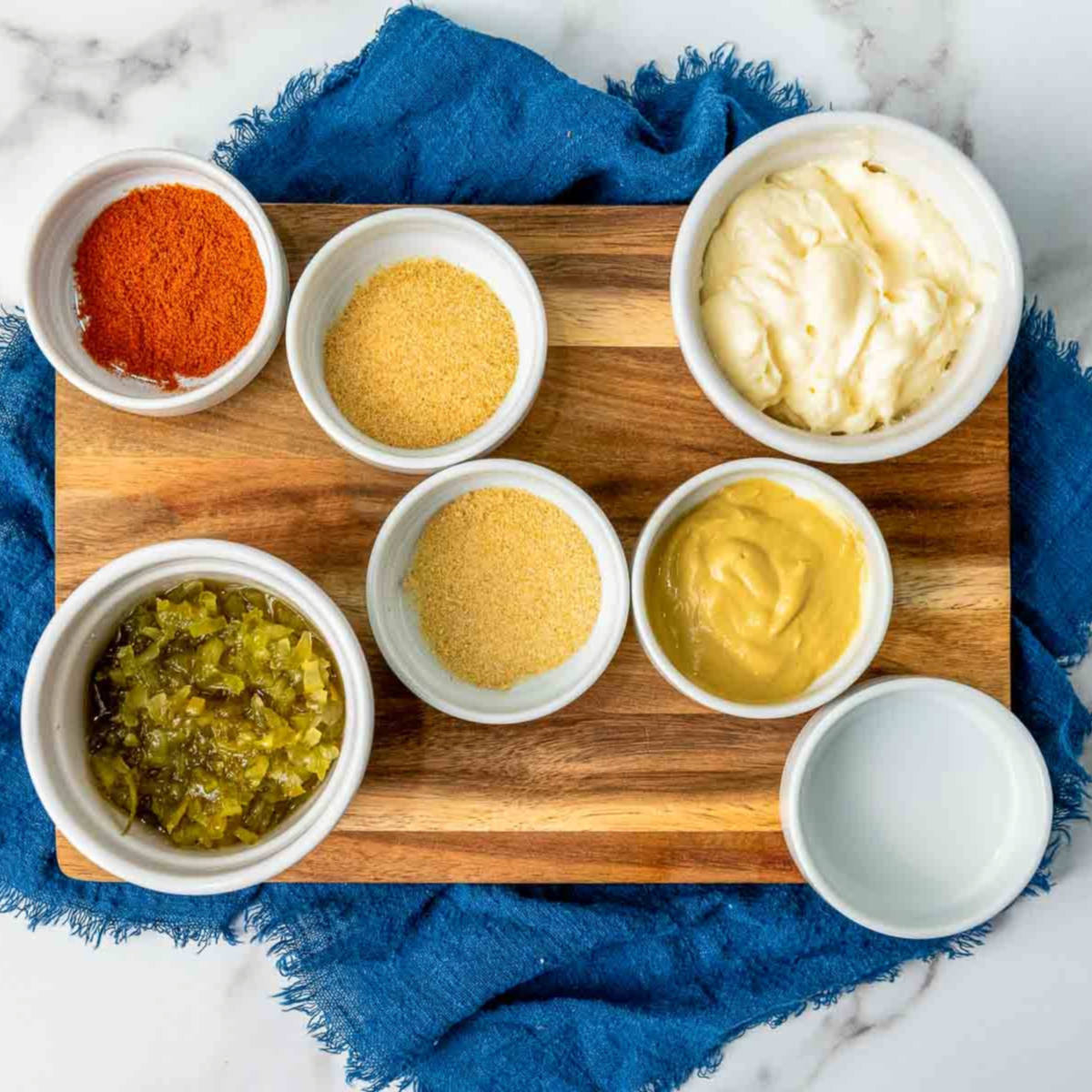 Ingredients to make big mac sauce placed on a wooden board.