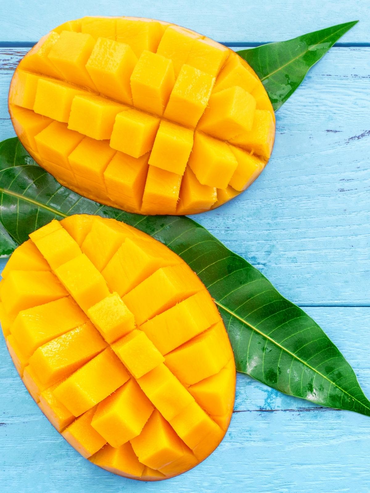 Two slices of mangoes placed on a blue surface.