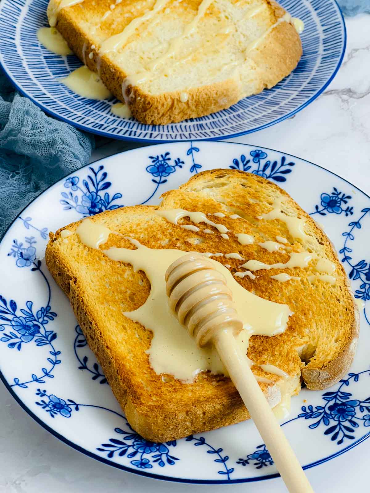 Side view of a toasted bread on a plate with whipped honey splashed on it.