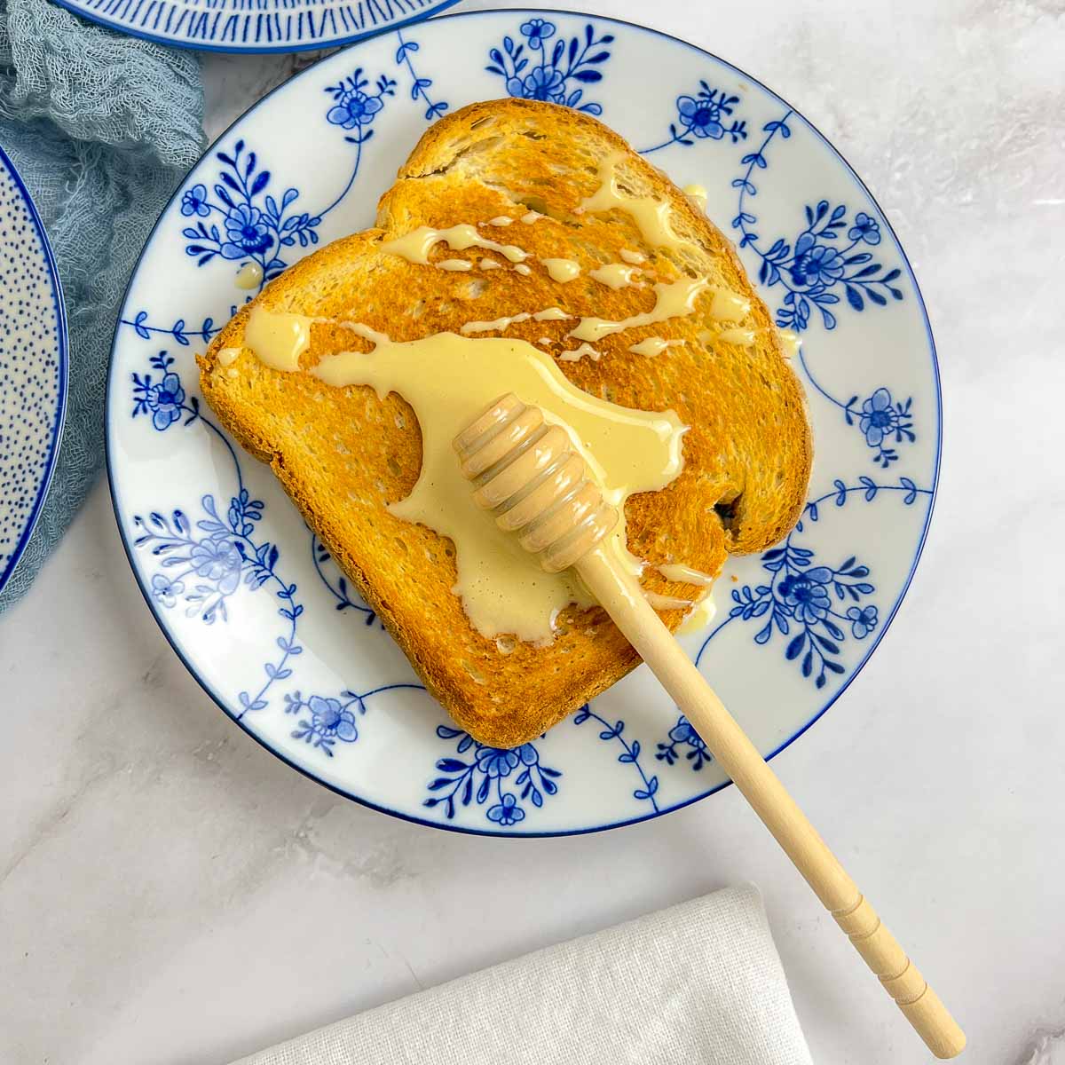 Whipped honey spread on a toasted bread using a honey stick.