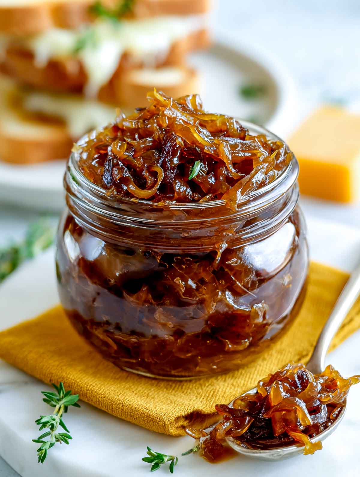 Jar of caramelized onion relish with a spoonful beside it on a kitchen surface.