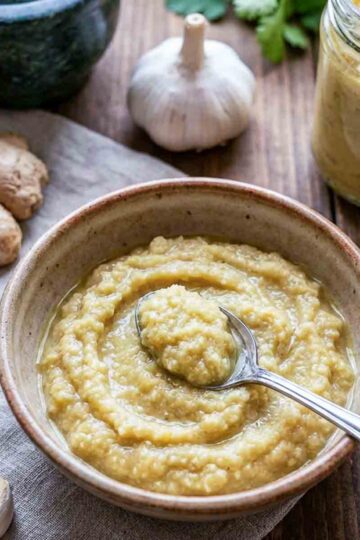 A bowl of fresh ginger garlic paste with a spoon inside.