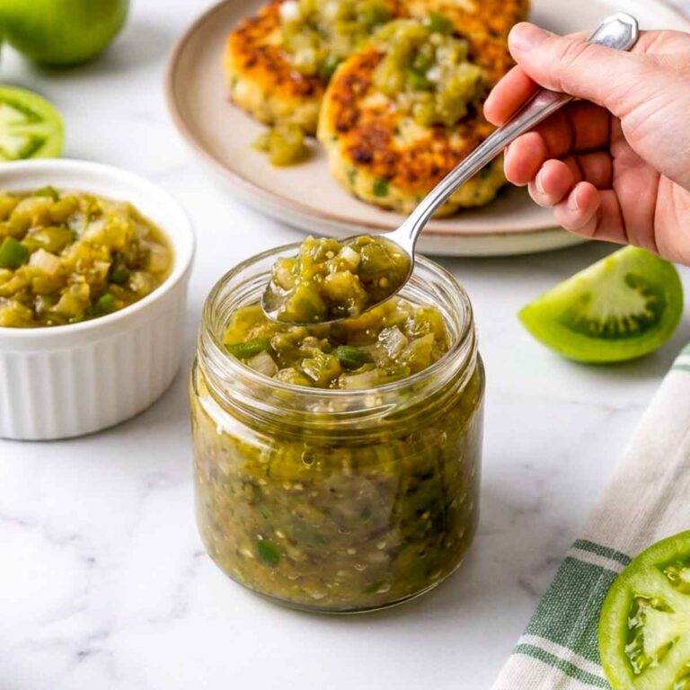 Woman holding a spoonful of green tomato relish over the jar.