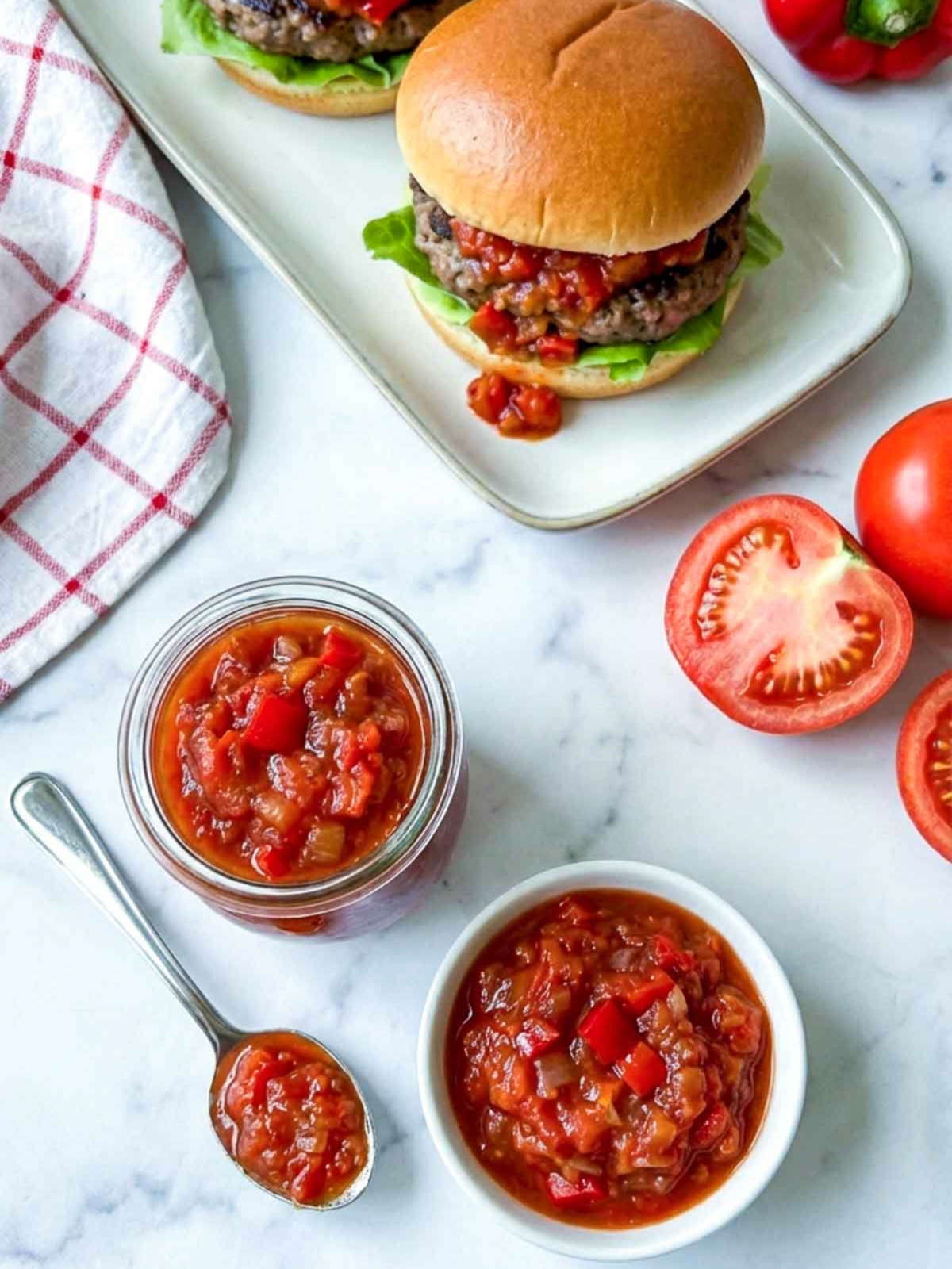 Top view of red hamburger relish with burgers in the background.