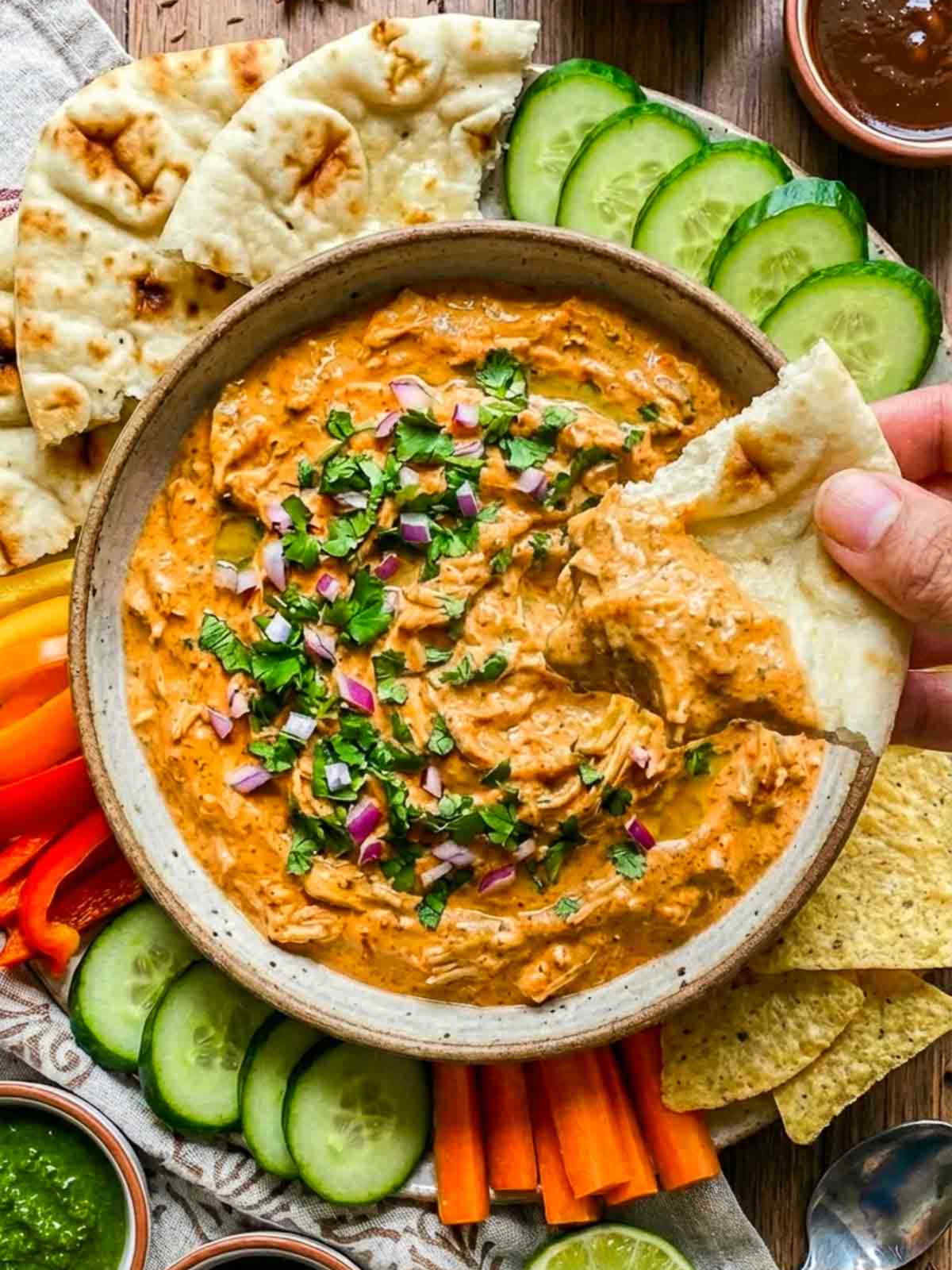 Hand dipping a naan bread into tandoori chicken dip.