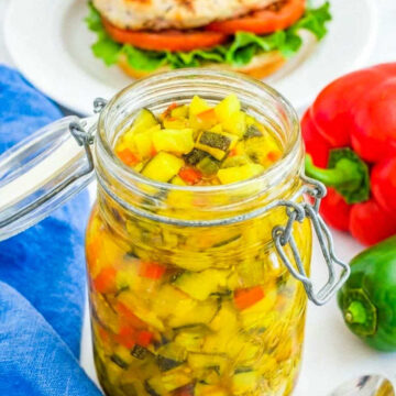 ar of homemade zucchini relish with diced zucchini and peppers in brine, served beside a chicken sandwich.