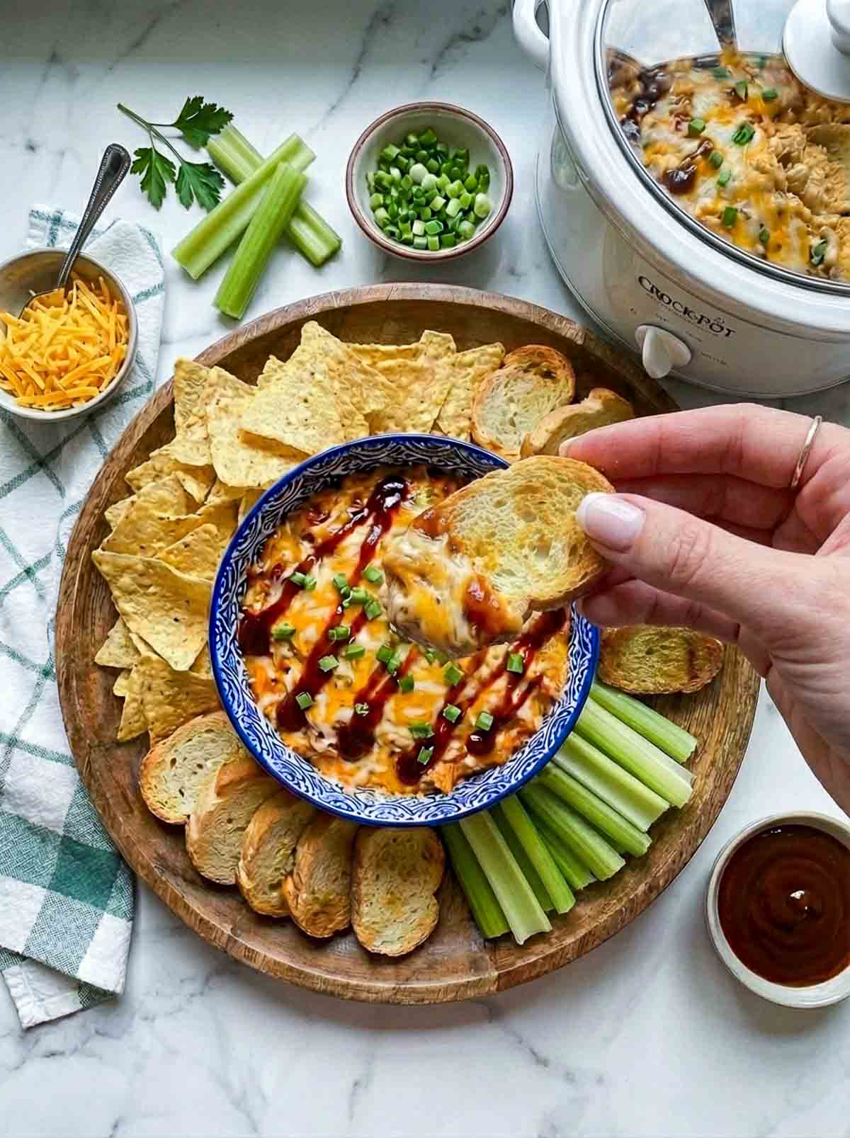 A persona scooping out bbq chicken dip using a bread as a dipper.