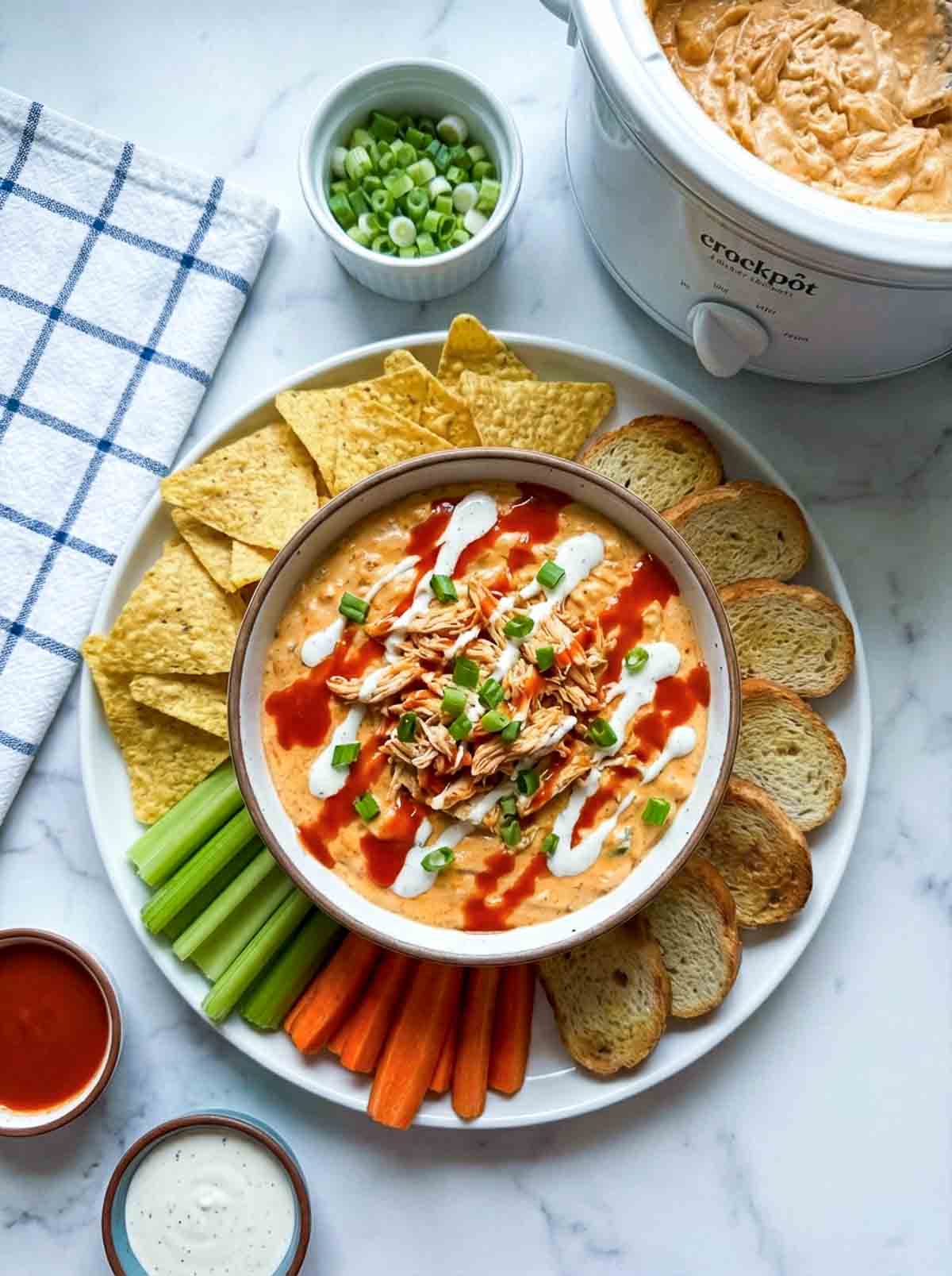 Buffalo chicken dip with chips, veggies, and bread slices
