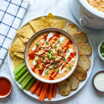 Buffalo chicken dip with chips, carrots, celery, bread, and sauces