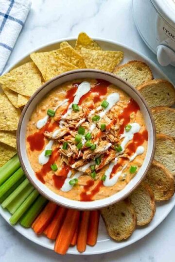 Buffalo chicken dip with chips, carrots, celery, bread, and sauces