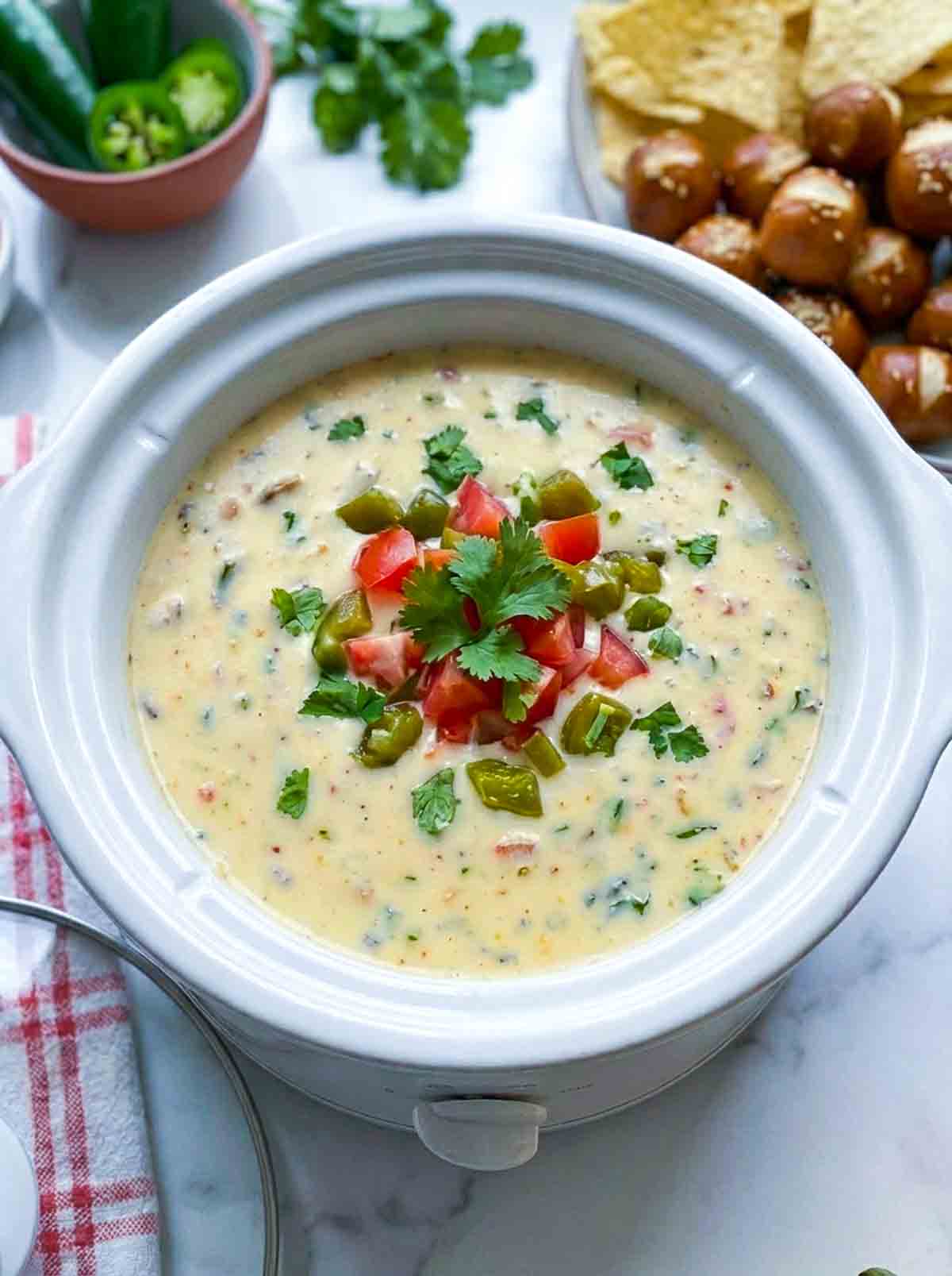 Cheesy queso dip made in a crockpot and placed on a white marble surface.